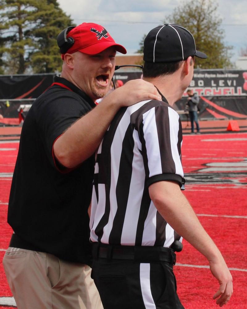 Head coach Aaron Best talking with a referee after a personal foul penalty, at the Red-White spring game. 