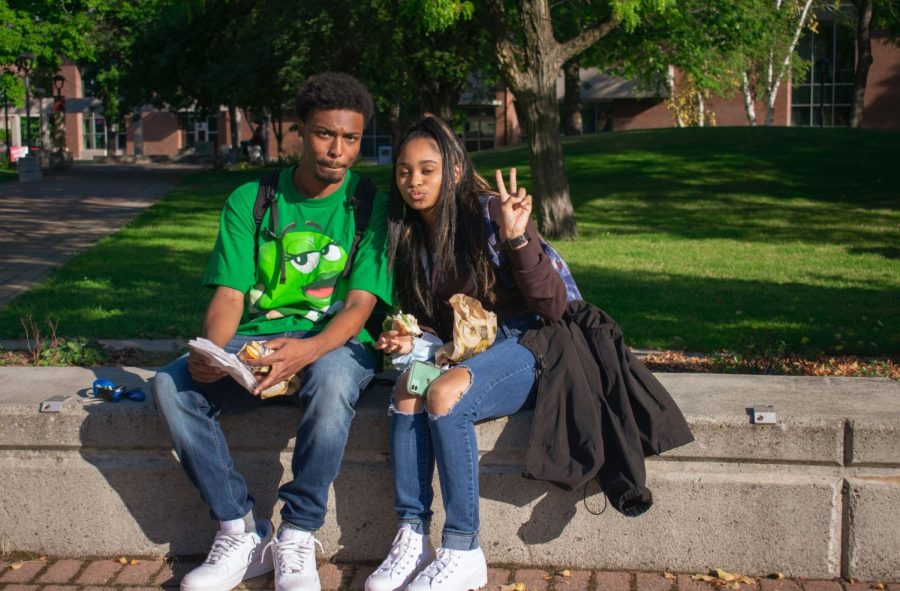 Two students chill on campus and enjoy the warm fall day.