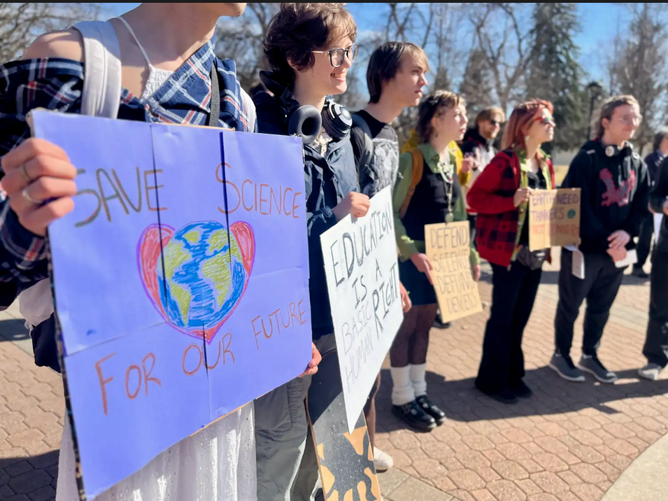 Protesters stand with signs in the Arevalo Campus Mall on March 7.